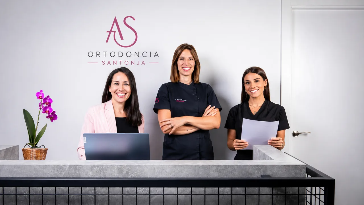Equipo de Ortodoncia Santonja en la recepción de la clínica de Las Rozas, bajo el logotipo AS