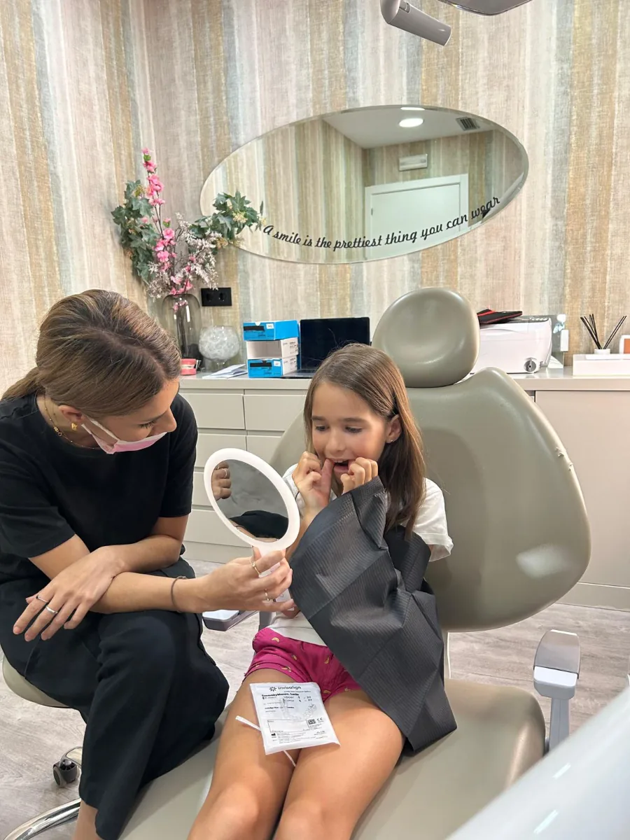Niña mirándose en el espejo junto a la Dra. Santonja en su revisión de ortodoncia infantil en Las Rozas