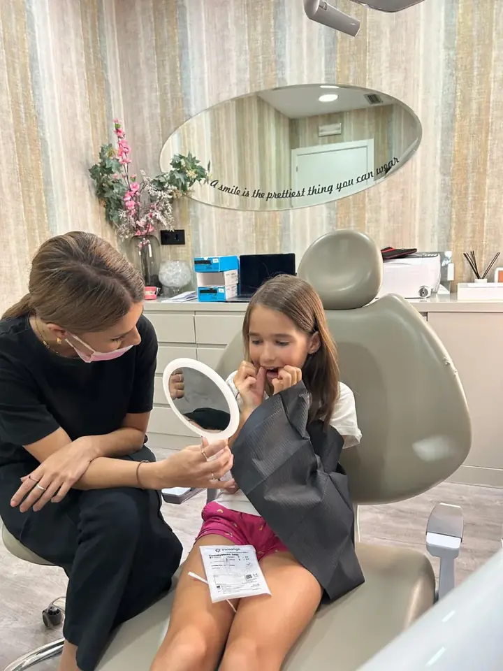 Niña mirándose en el espejo junto a la Dra. Santonja en su revisión de ortodoncia infantil